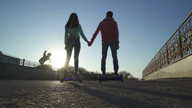 Man And Woman Hold Hands And Ride On Hover Board