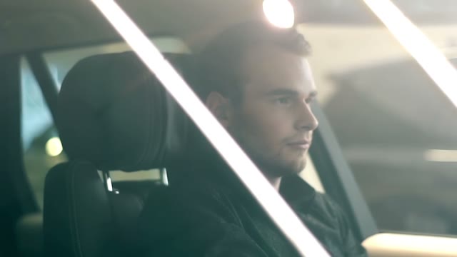 Young Man Sitting At The Wheel Of An Expensive Car
