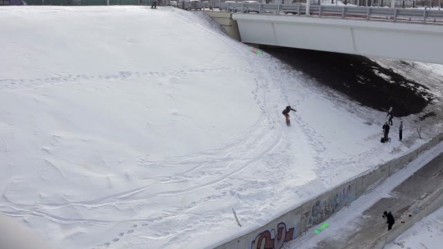 Snowboarder Jumping Over The Street Gap Near The Bridge And Falls