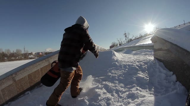 Snowboarder Goes Near The Street Ladge On The Sun Background