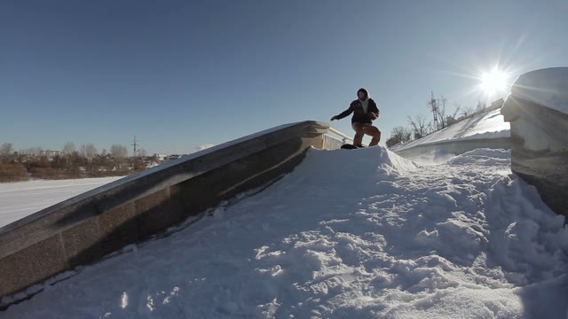 Snowboarder Doing A Slide Trick On A Ledge In The Street