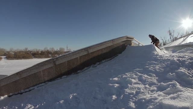 Snowboarder Doing A Slide Trick On A Ledge In The Street