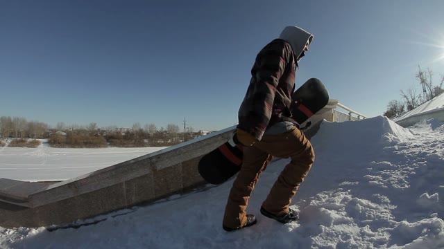 Snowboarder Goes Near The Street Ladge On The Sun Background