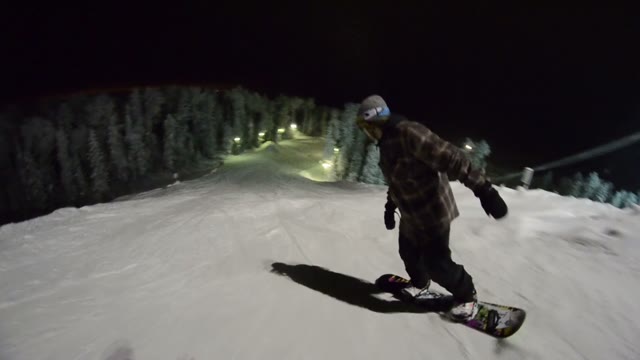 Snowboarder Starts To Move Down The Mountain And Doing Tricks At Night