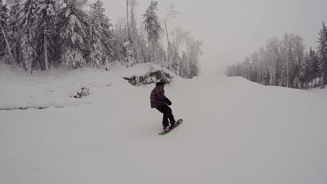 Snowboarder Jumping From Kicker Then Slides On The Rail In Snowpark
