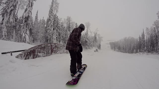 Snowboarder Jumping From Kicker Then Slides On The Rail In Snowpark