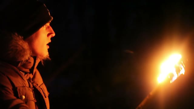 Scared Young Man Looks Around With The Torch At Night In The Winter Forest