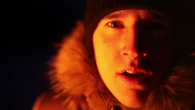 A Young Guy Fright Looks At The Camera. Illuminated A Fire