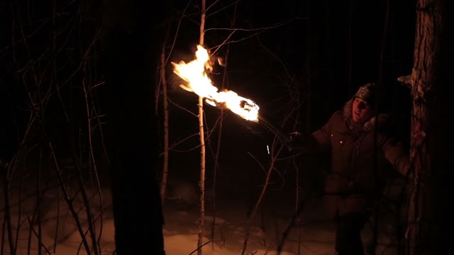 Young Man Goes Through The Snowy Winter Forest At Night With The Torch