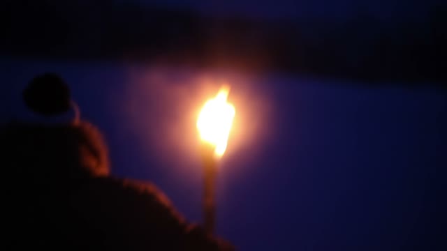 A Young Guy With The Torch Goes Through The Snow-covered Field At Night