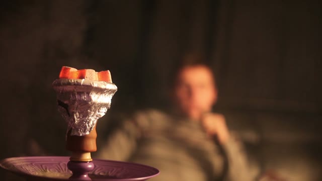Close-up Of Hookah Coals. A Man Smokes A Hookah In The Background