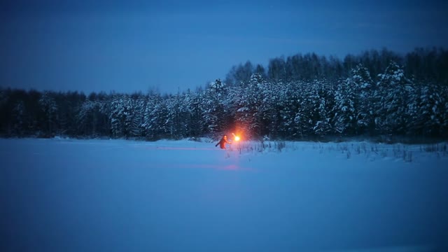 A Young Guy With The Torch Goes Through The Snow-covered Field At Night