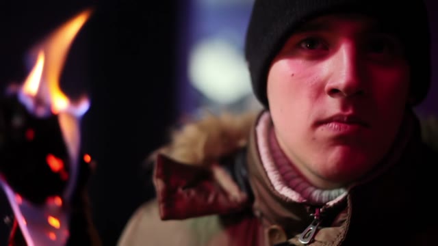 Young Man In Jacket And Hat Holding A Torch Andlooking Somewhere