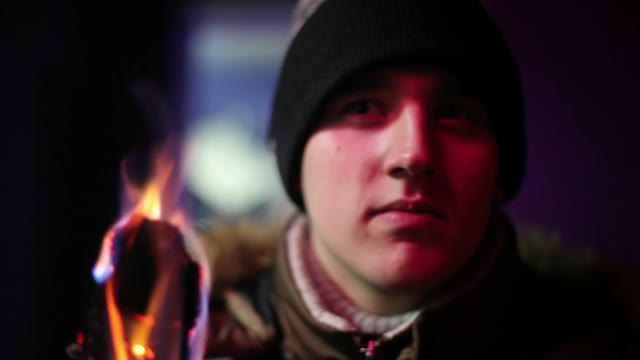 Young Man In Jacket And Hat Holding A Torch Andlooking Somewhere