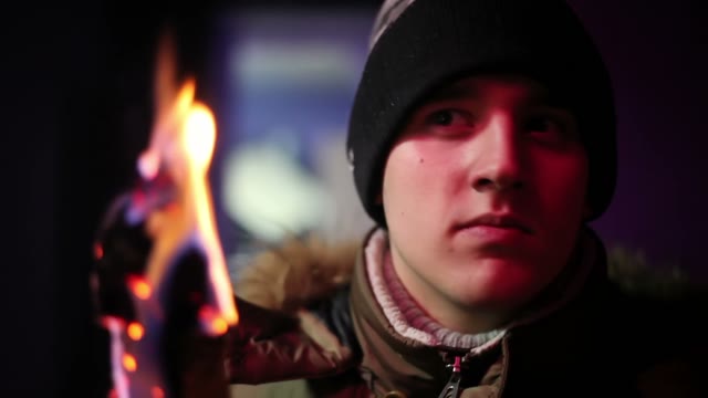 Young Man In Jacket And Hat Holding A Torch Andlooking Somewhere
