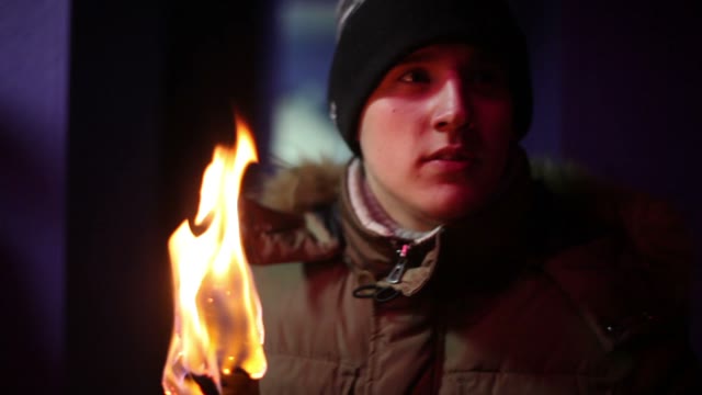 Young Man In Jacket And Hat Holding A Torch Andlooking Somewhere