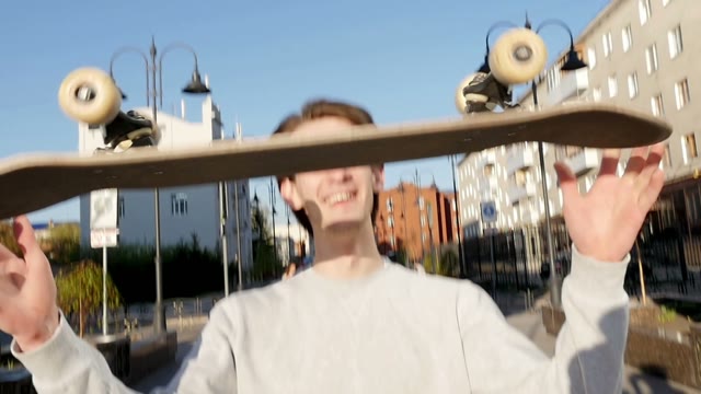Young Man Smiles And Throws A Skateboard In Hands