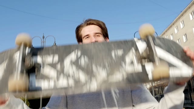 Young Man Smiles And Throws A Skateboard In Hands