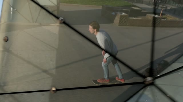 Man Rides A Skateboard. Shooting In The Reflection Of A City Sculpture
