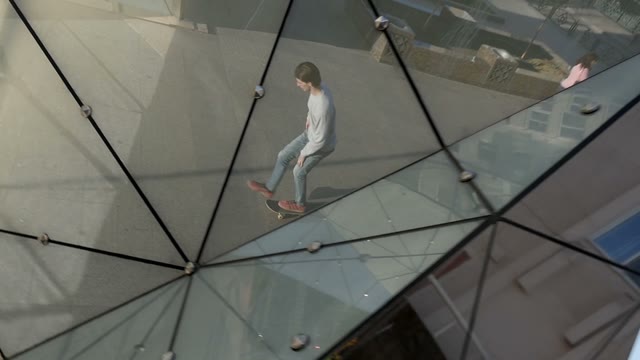 Man Rides A Skateboard. Shooting In The Reflection Of A City Sculpture
