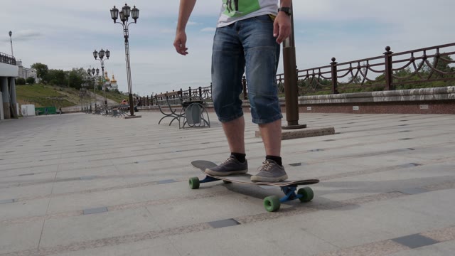 A Young Guy Riding A Longboard Along The Waterfront And Makes Tricks