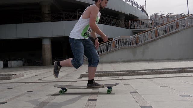 A Young Guy Riding A Longboard Along The Waterfront And Makes Tricks