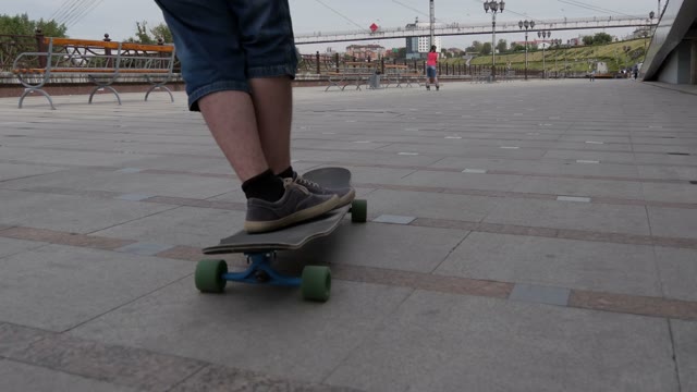 Man Riding His Longboard On The Embankment Of The River