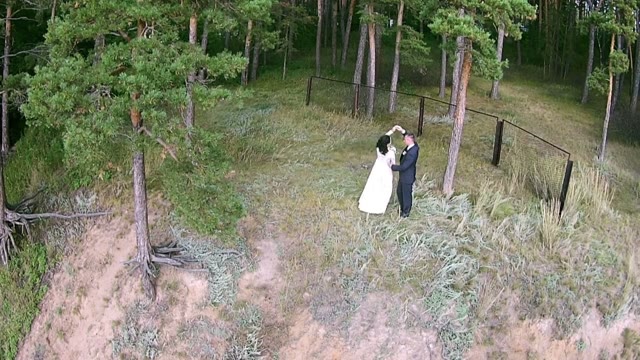 Newlyweds Dancing In The Coniferous Forest In Front Of Camera