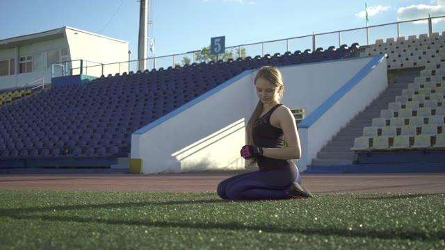 Young Athlete Woman Sitting On The Lawn In The Stadium