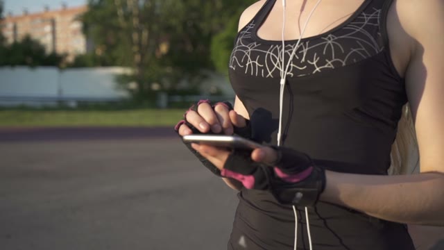 Young Athlete Woman Walking Down The Street, And Enjoys The Phone