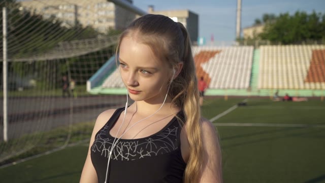 Young Woman Athlete Goes Through The Stadium With Headphones In Their Ears