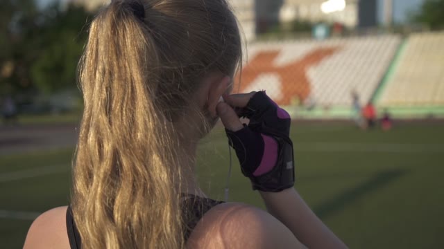 Young Woman Athlete Goes Through The Stadium With Headphones In Their Ears