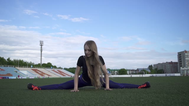 Young Female Athlete Doing Stretching And Sits On Twine
