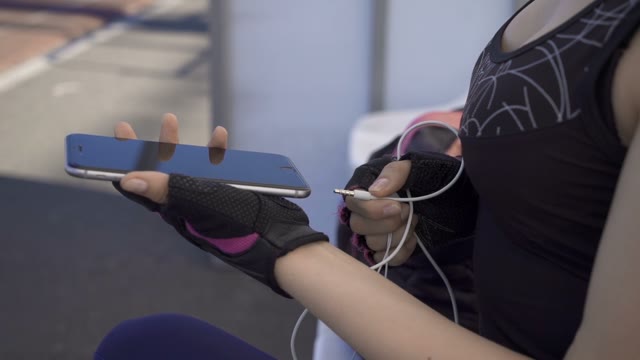 Young Athlete Woman Inserts The Headphones To The Phone