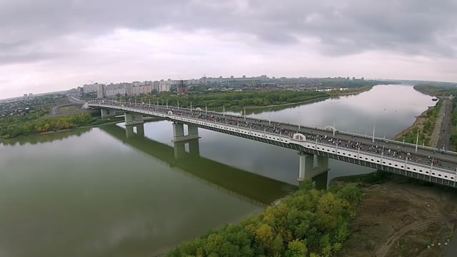 People Run A Marathon On The Road Bridge Across The River