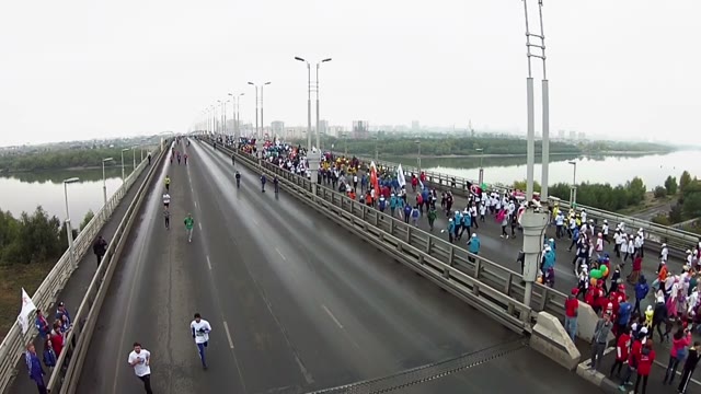 Young People Run A Marathon On A Large Bridge Across The River