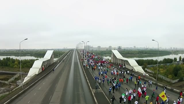 Young People Run A Marathon On A Large Road Bridge Across The River