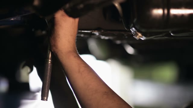 Mechanic Tightening The Screws Under The Machine