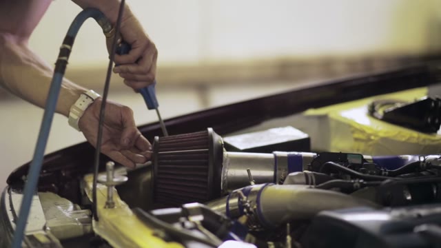 Worker Blows Away The Dust Off The Car Engine