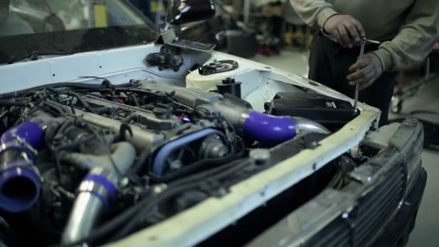 Mechanic Twists The Screws In The Hood Of The Car
