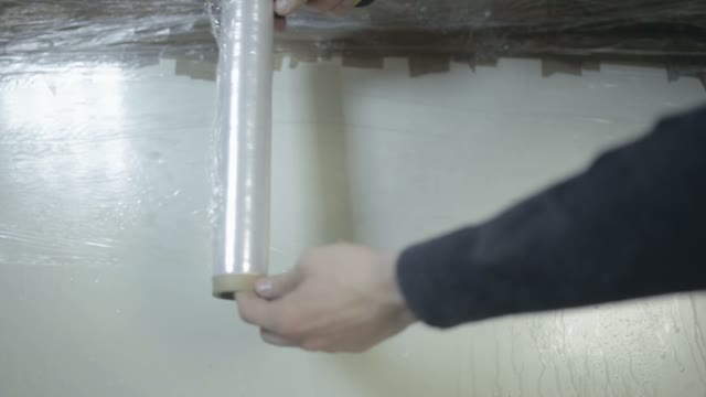 Two Men Unwrap The Packing Tape