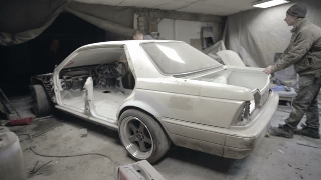 Disassembled Car Roll Out Of The Garage Workers