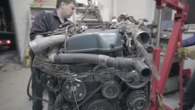 Experienced Workers Move The Car Engine