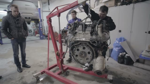 Group Workers Move The Car Engine