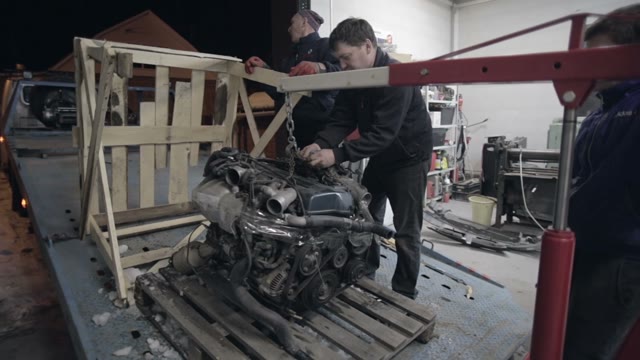 Workers Group Put The Car Engine On The Truck