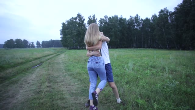 Young Couple Embracing And Kissing On Summer Field. The Girl Holding A Kite