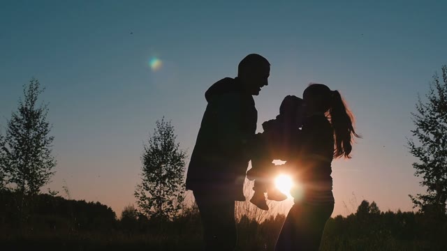 A Married Couple With A Child Playing At Sunset