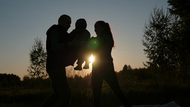 Newlyweds Play With A Child At Sunset