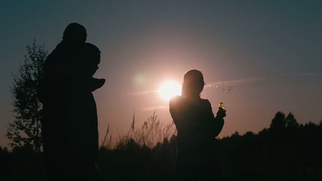 Happy Couple With A Small Child Playing With Soap Bubbles On Nature
