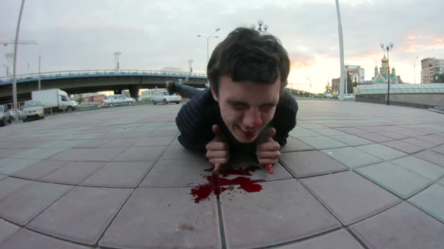 Young Man Lying On The Sidewalk And Bleeding